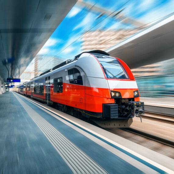 High speed train in motion on the train station at sunset in Vienna, Austria. Red modern intercity passenger train with motion blur effect. Railway platform. Railroad. Commercial transportation